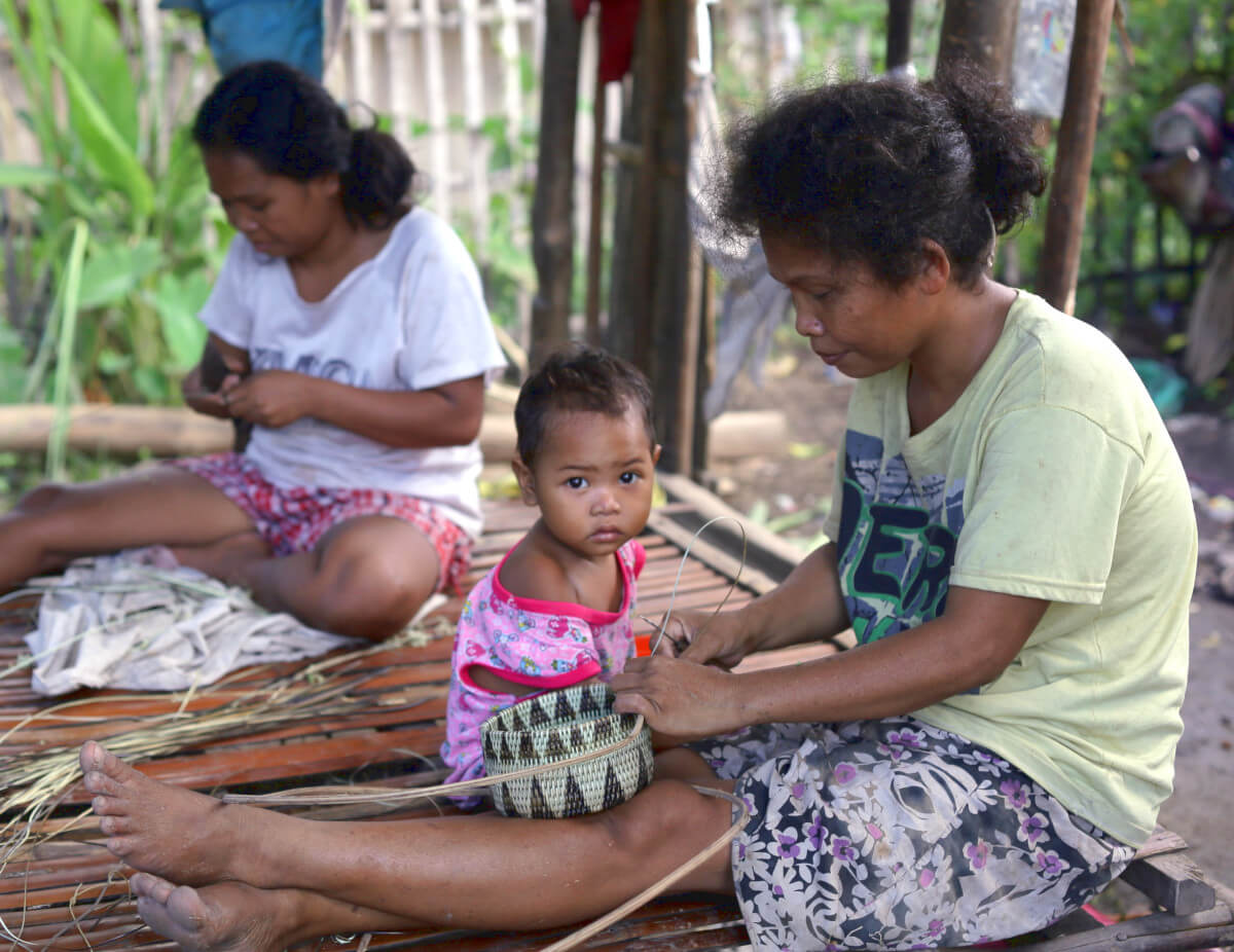 femmes vannières fabriquant des paniers d'osier aux Philippines, avec un enfant